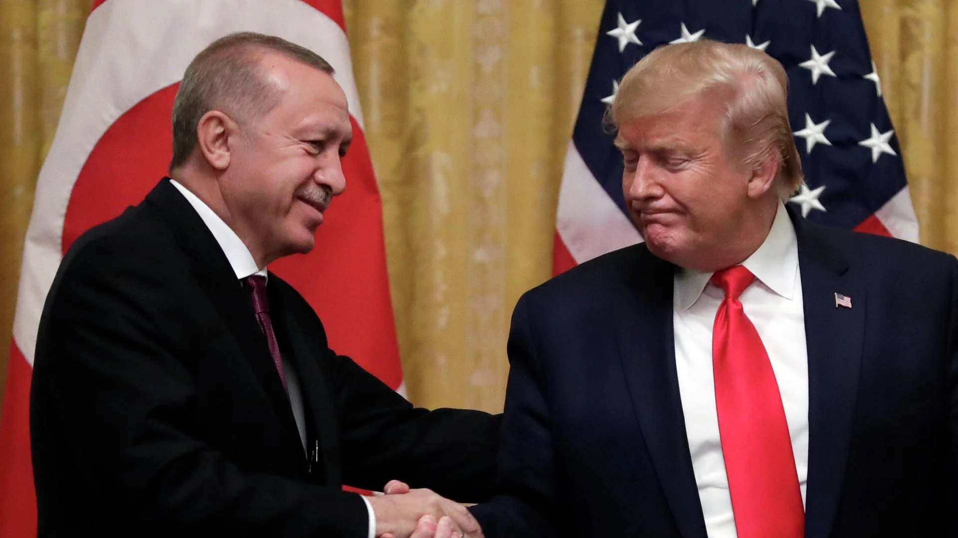 Эрдоган и Трамп пожимают руки на фоне флагов Турции и США
