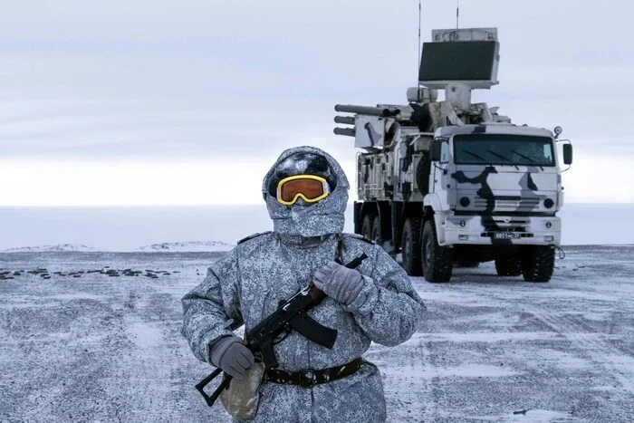 Російський військовий у камуфляжі з технікою на тлі Арктики
