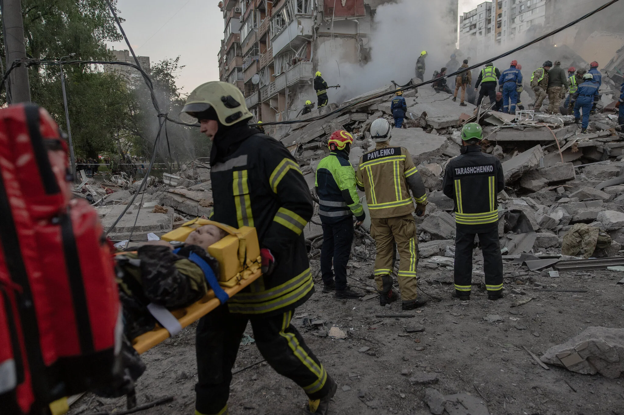 Рятувальники несуть пораненого на ношах біля завалів зруйнованого будинку