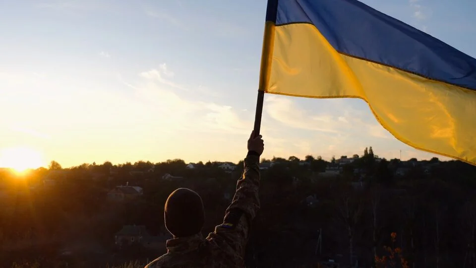 Військовий піднімає прапор України над звільненим селом на Дніпропетровщині