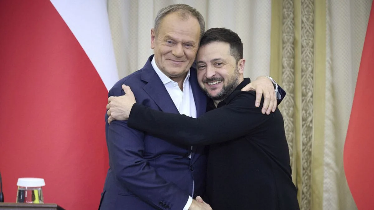 Володимир Зеленський і Дональд Туск обіймаються на тлі польських прапорів