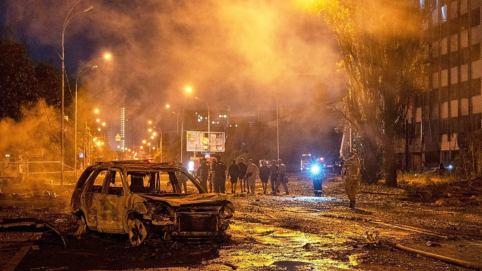 Згорілий автомобіль серед диму і людей на вулиці вночі