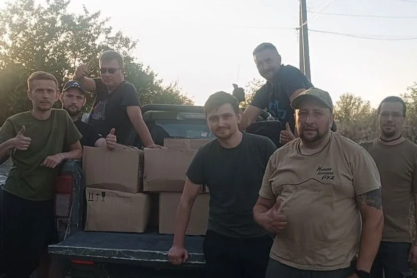 Волонтери біля пікапа з картонними коробками допомоги на узбіччі