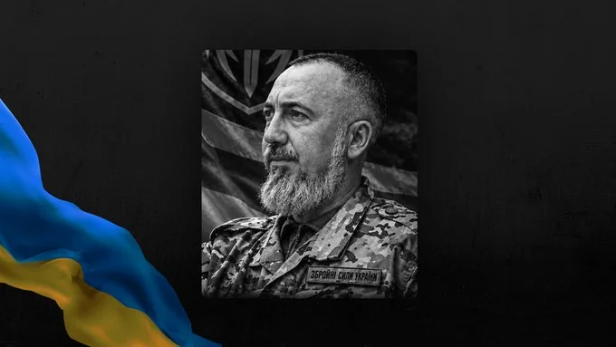 Чорно-білий портрет бородатого військового ЗСУ на тлі українського прапора
