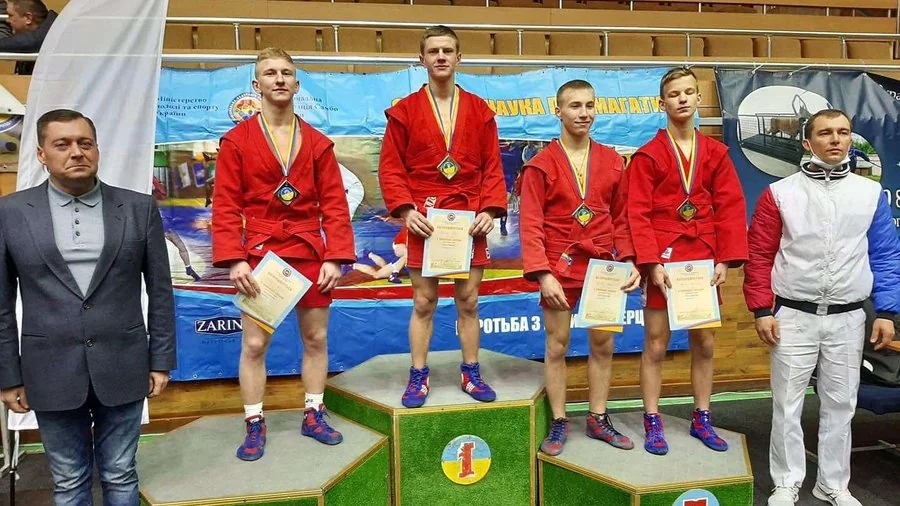 Юнаки в червоних куртках з медалями і дипломами стоять на подіумі