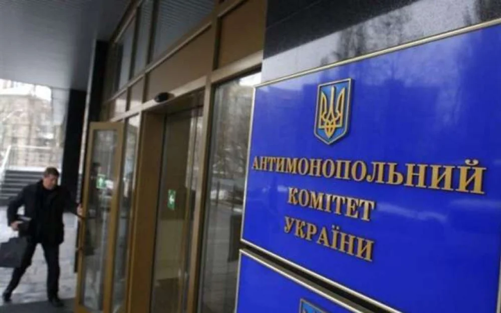 Чоловік виходить з будівлі Антимонопольного комітету України біля синьої таблички