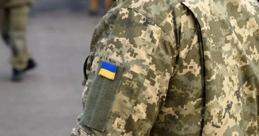 Спина військовослужбовця в піксельному камуфляжі з прапором України на рукаві