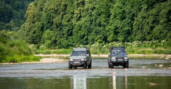 Два позашляховики їдуть річкою серед зеленого лісу