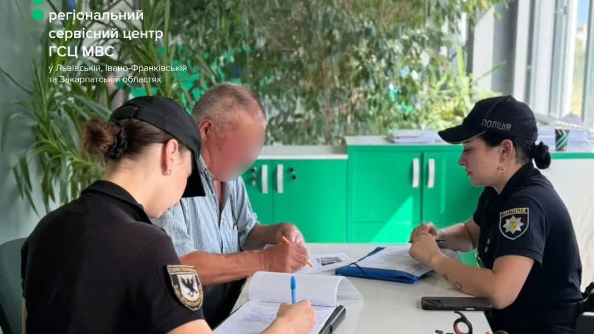 Поліцейські та чоловік за столом оформлюють документи в сервісному центрі МВС