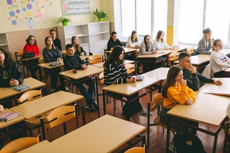 Школярі сидять за партами в світлому класі під час уроку