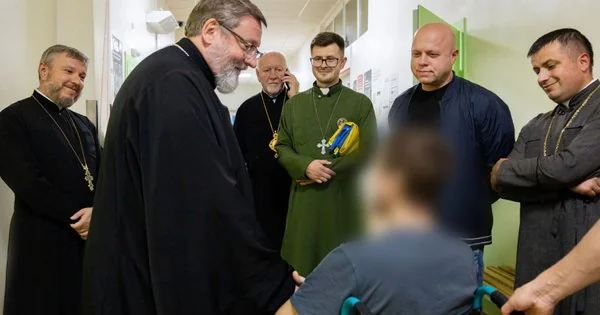 Священики УГКЦ біля пораненого захисника у візку в лікарняному коридорі