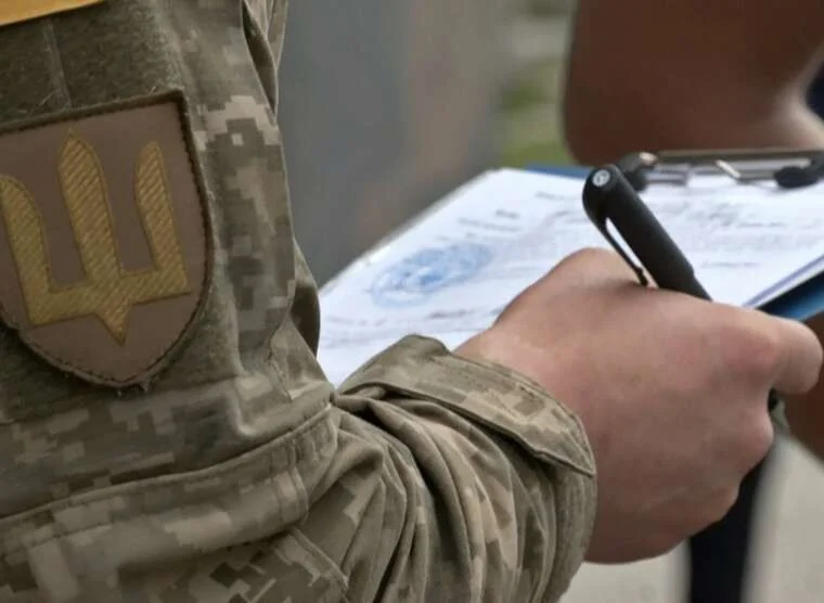 Військовий у пікселі з шевроном ЗСУ тримає планшет із документами
